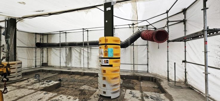 Binnenaanzicht van een afgesloten werkzone met ventilatieslangen die stof afvoeren en verse lucht aanvoeren.